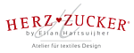 Logo mit dem Schriftzug 'HERZ-ZUCKER' in roter, gebogener Großschrift über einem stilisierten weißen Herz mit einem Zickzack-Muster
