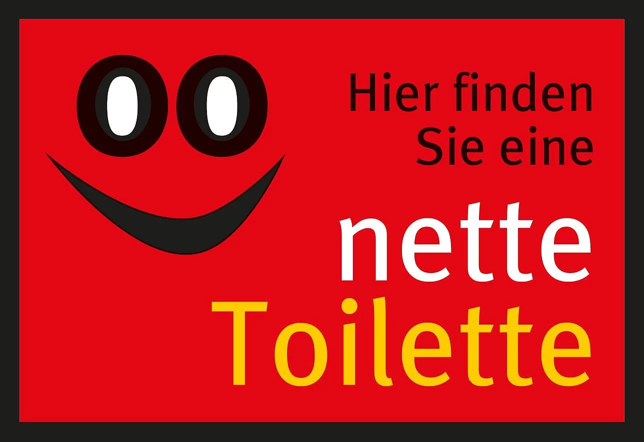 Rotes Rechteck mit stilisiertem Gesicht aus zwei weißen Augen und einem schwarzen Lächeln sowie dem Text 'Hier finden Sie eine nette Toilette' in Schwarz, Weiß und Gelb