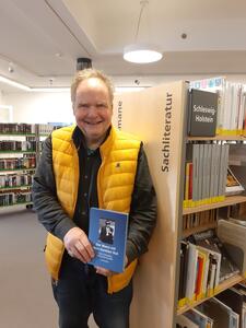 Bild vergrößern: Axel Winkler mit  seinem neustes Buch »Der Mann mit dem dunklen Hut« in der Stadtbücherei